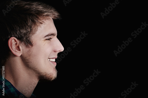 Happy young student man smiling isolated on black background.