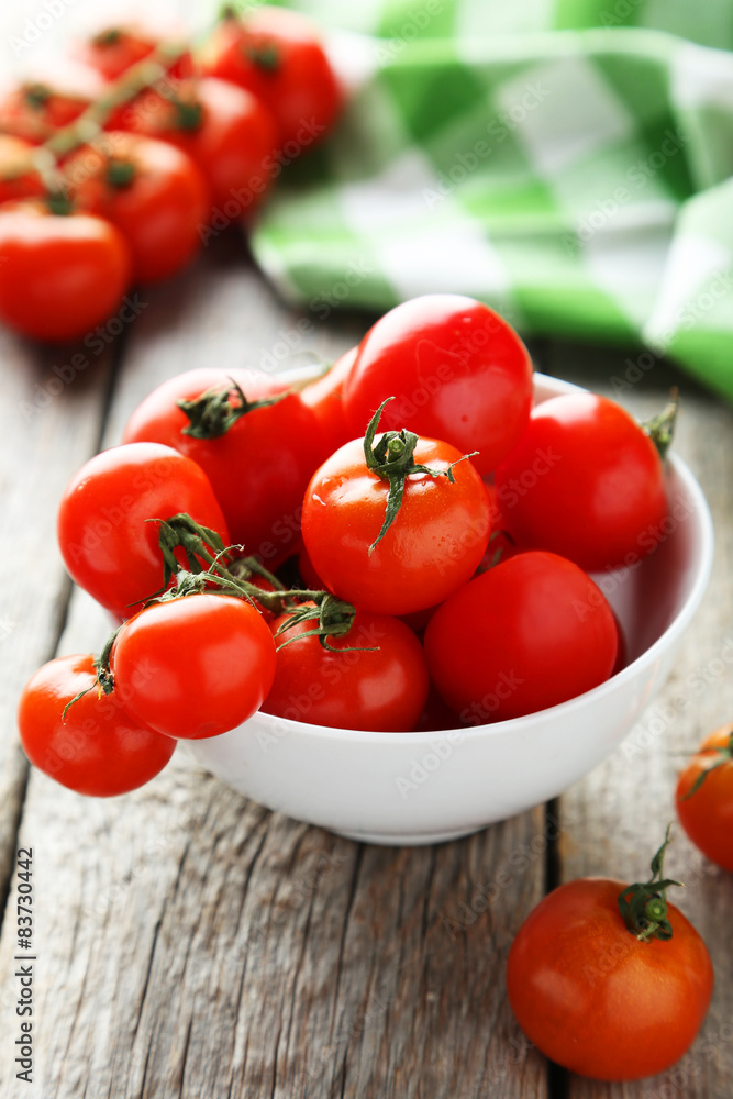 Fresh cherry tomatoes in bowl on grey wooden background Fresh cherry tomatoes in bowl on grey wooden background