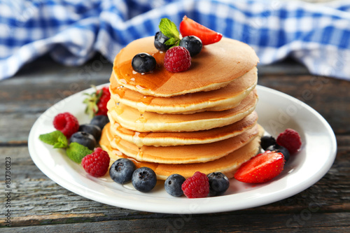 Delicious pancakes with berries on blue wooden background