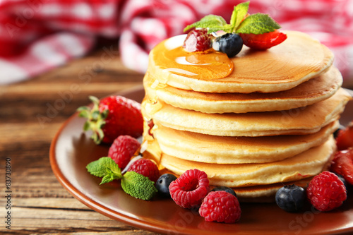 Delicious pancakes with berries on brown wooden background