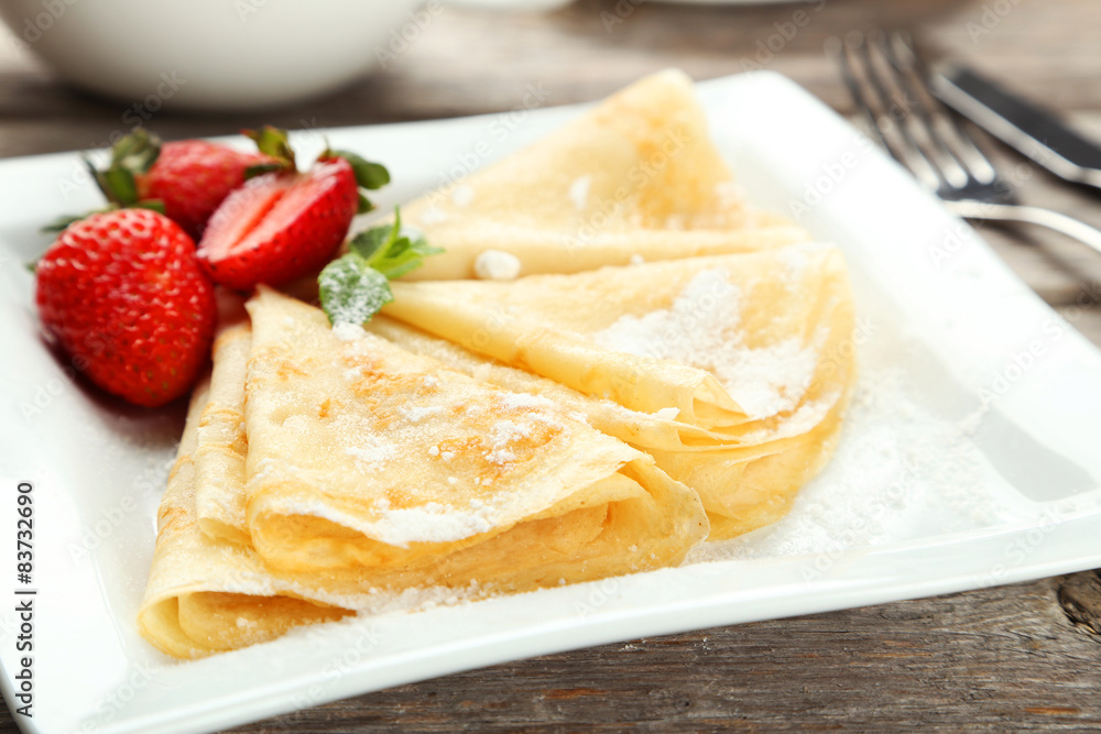 Pancakes with strawberry on plate on grey wooden backgound Pancakes with strawberry on plate on grey wooden backgound