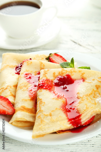 Pancakes with strawberry on plate on white wooden backgound
