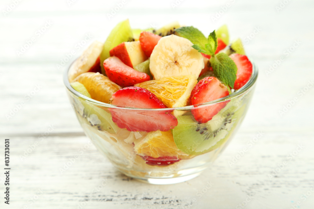 Fresh fruit salad in bowl on white wooden background Fresh fruit salad in bowl on white wooden background