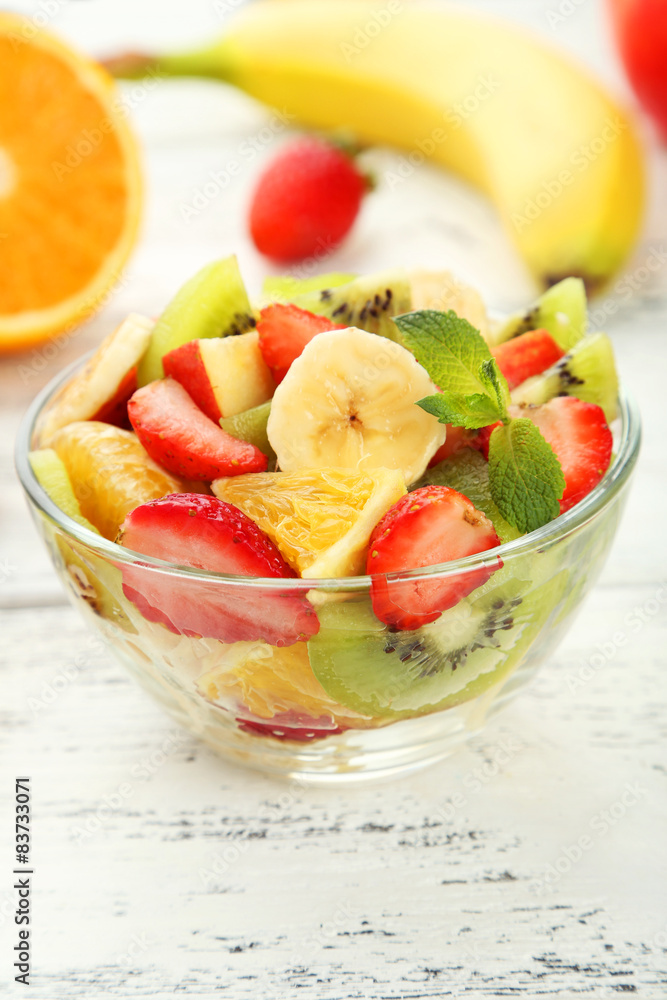 Fresh fruit salad in bowl on white wooden background Fresh fruit salad in bowl on white wooden background