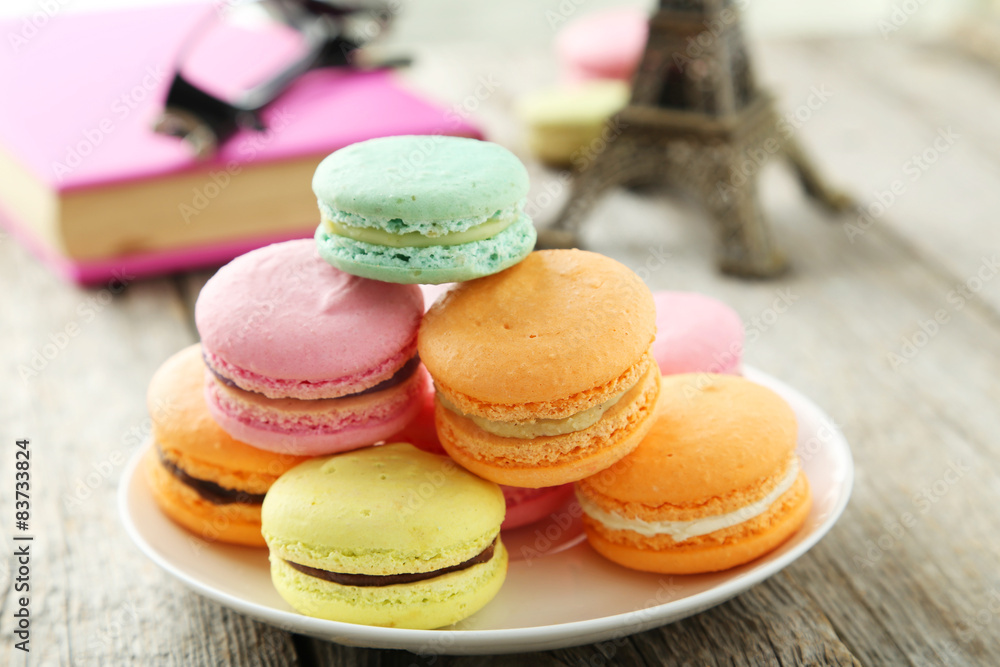 French colorful macarons on plate on grey wooden background