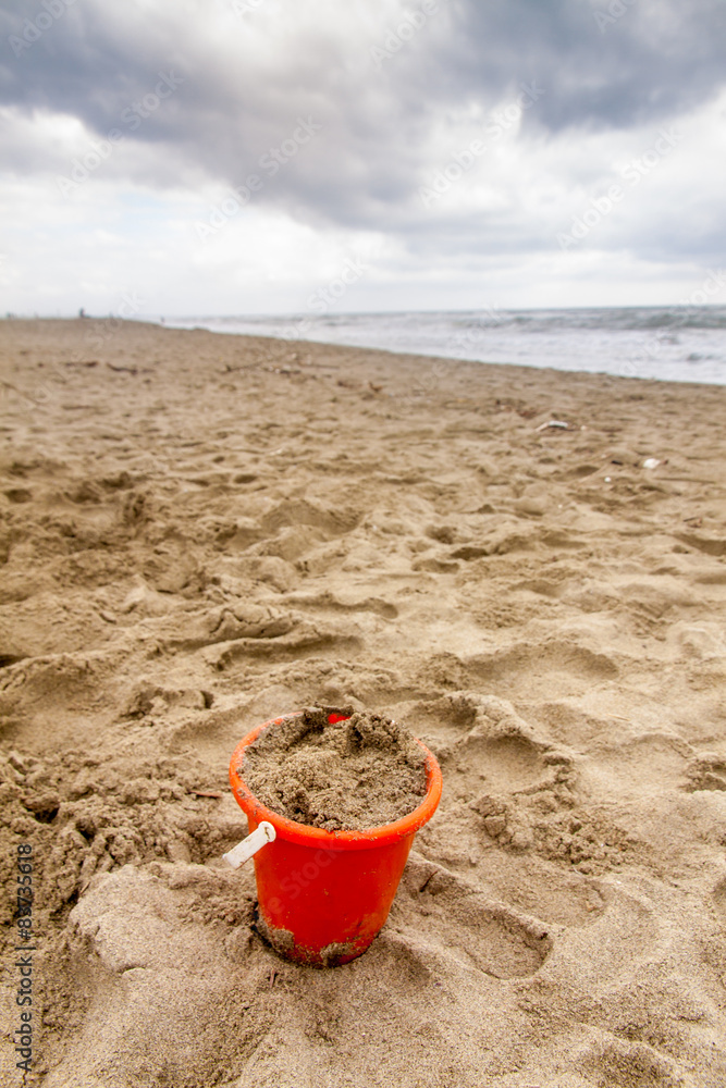Bucket full of sand on the beach in a cloudy day Bucket full of sand on the beach in a cloudy day