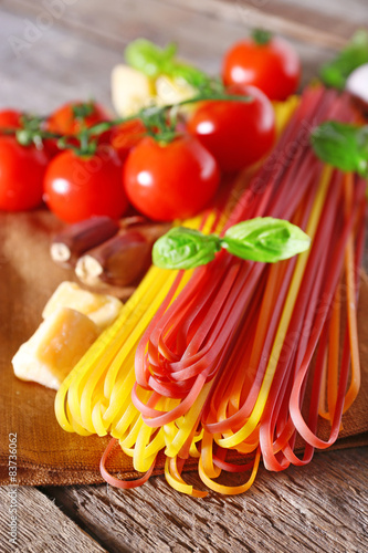 Pasta with cherry tomatoes and other ingredients on wooden table background