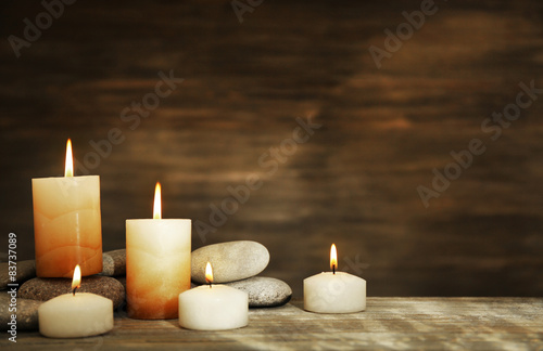 Beautiful composition with candles and spa stones on wooden background