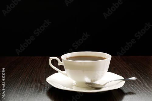 Cup of coffee on wooden table  on dark background