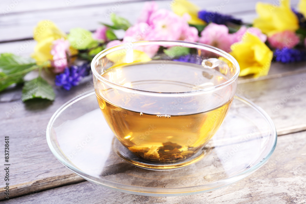 Cup of herbal tea with flowers on wooden table, closeup