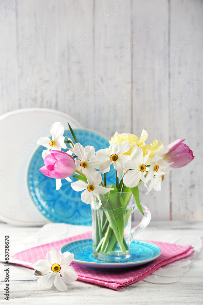 Spring bouquet in glass mug on color wooden background Spring bouquet in glass mug on color wooden background