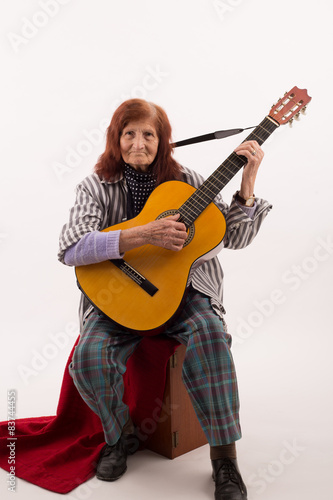 Funny elderly lady playing acoustic guitar. © lesnoj
