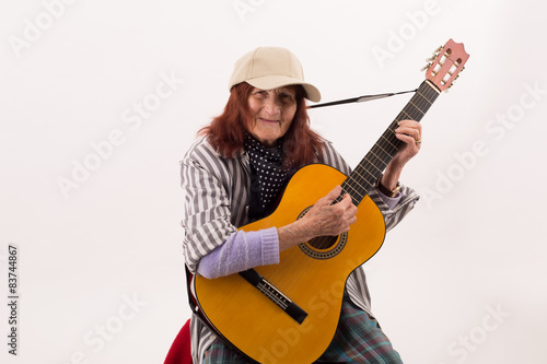 Funny elderly lady playing acoustic guitar.