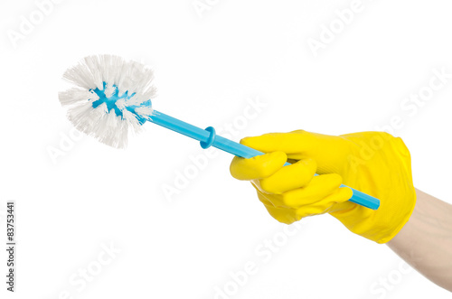 human hand holding a blue toilet brush in yellow gloves