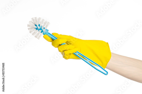 human hand holding a blue toilet brush in yellow gloves