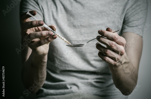 addict holding spoon lighter and heats the liquid drug