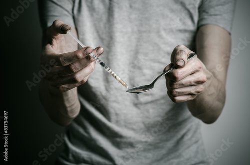 addict holding spoon lighter and heats the liquid drug