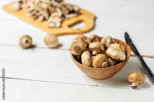 Sliced champignons on board and wooden bowl