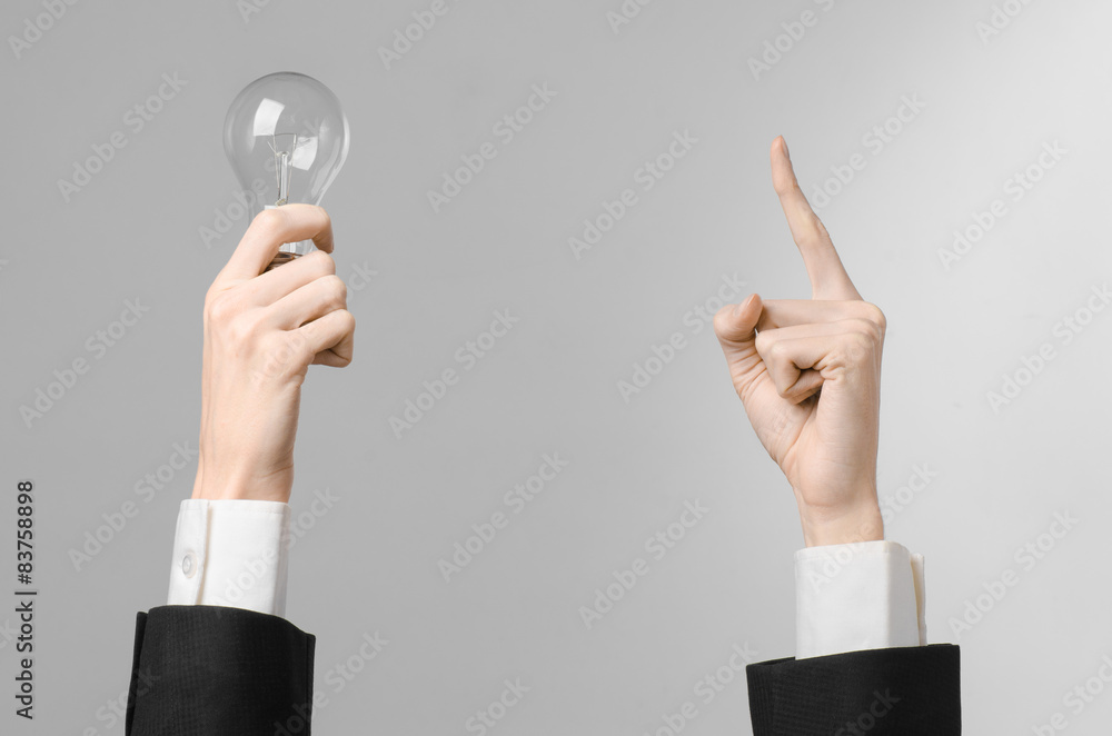 man's hand in a black suit holding a light bulb in studio man's hand in a black suit holding a light bulb in studio
