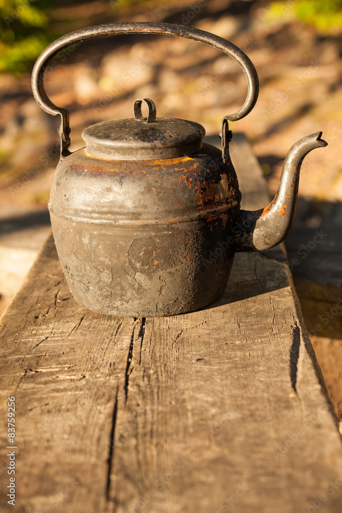 Old kettle in wooden bench outdoors Old kettle in wooden bench outdoors
