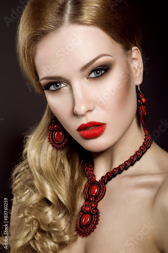Beautiful blonde woman with evening make-up and red lips. Picture taken in the studio on a black background.
