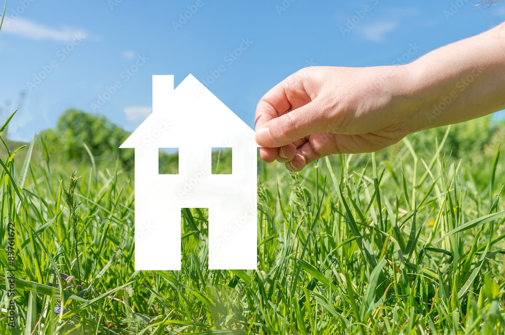 Hand holding cut off paper house as symbol of mortgage Hand holding cut off paper house as symbol of mortgage