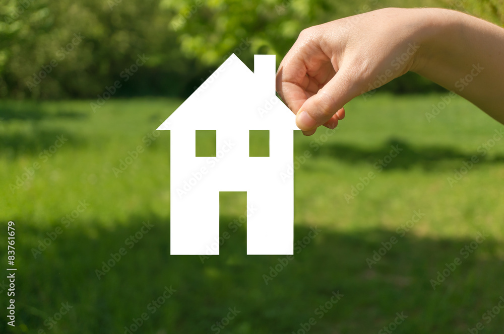 Hand holding cut off paper house as symbol of mortgage Hand holding cut off paper house as symbol of mortgage