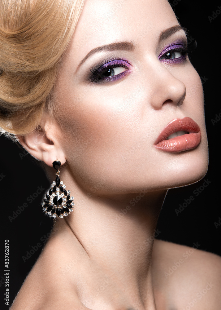 Beautiful girl with bright makeup and evening hairstyle. Picture taken in the studio on a gray background.