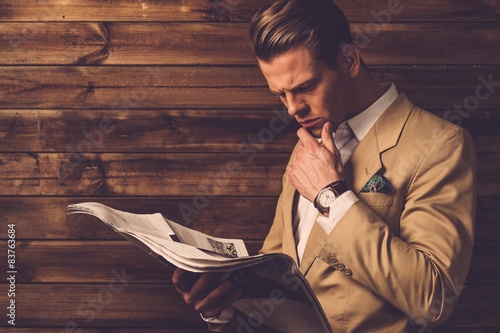 Fotografie Stylish man with newspaper in rural cottage interior