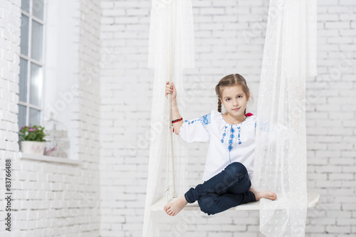 Young girl in embroidery on swing