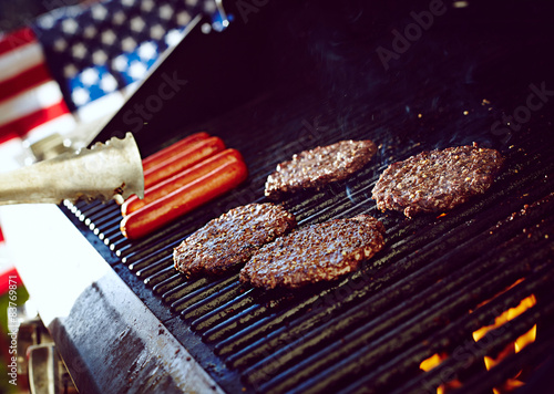 Burgers and hotdogs cooking over flames on grill
