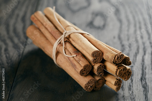 Fototapeta bunch of cinnamon sticks tied with twine, on rustic table