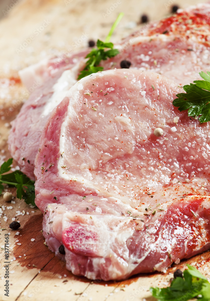 Raw meat steak with spices on a wooden board, selective focus Raw meat steak with spices on a wooden board, selective focus