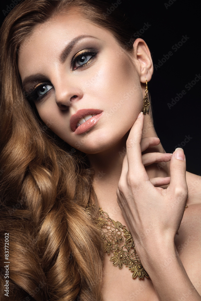 Obraz premium Beautiful brunette woman with perfect skin, bright makeup and gold jewelry. Beauty face. Picture taken in the studio on a grey background