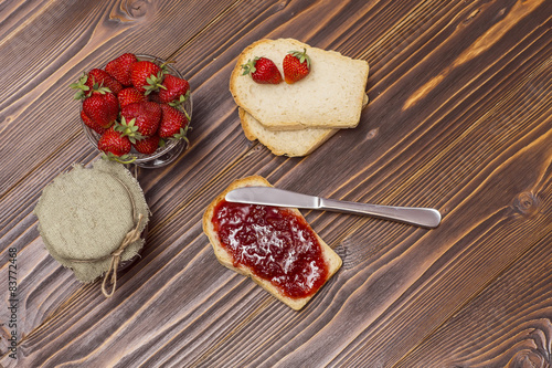 Strawberries and croissant on a wooden brown background