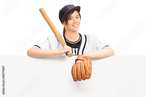 Young woman holding a baseball bat behind panel