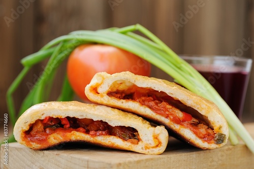 Two pieces of pizza calzone with glass of red wine, fresh scalli photo