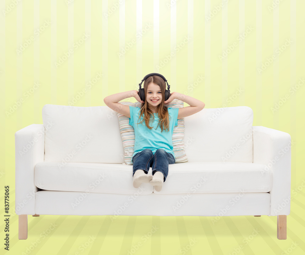 smiling little girl in headphones sitting on sofa smiling little girl in headphones sitting on sofa