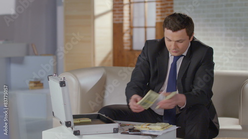 Overjoyed businessman grabs money from briefcase, success, greed photo