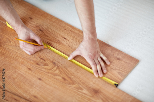 close up of male hands measuring flooring