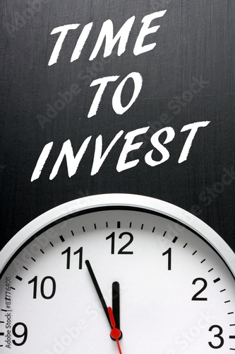 Time to Invest written on a blackboard above a clock face