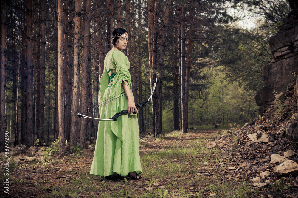 Elf woman with the magic bow on the forest background.