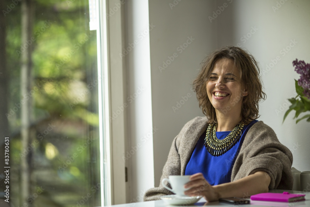 Woman laughing while sitting near the window of his house. Woman laughing while sitting near the window of his house.