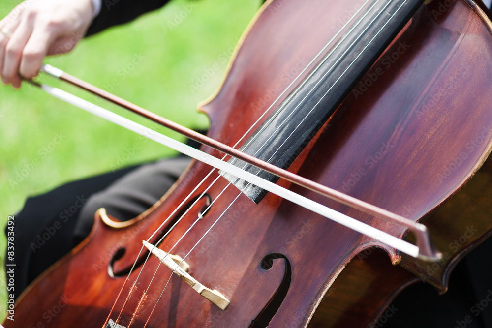 Man's hands playing violoncello outdoors Man's hands playing violoncello outdoors