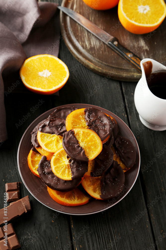Delicious slices of orange coated chocolate on plate Delicious slices of orange coated chocolate on plate