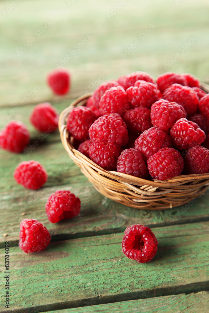 Raspberries in basket on green wooden background Raspberries in basket on green wooden background