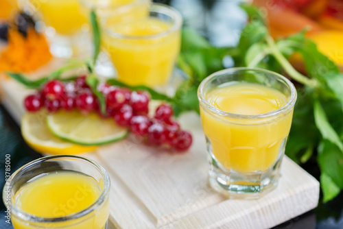 Set of several bright glasses with cold alcoholic cocktail with orange juice on a wooden table in a restaurant with ice and creative decoration of berries, fresh mint and orange slices. soft focus