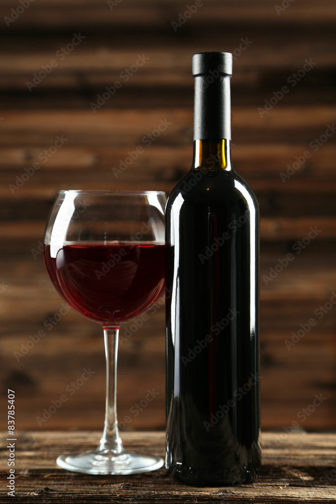 Red wine glass with bottle on brown wooden background