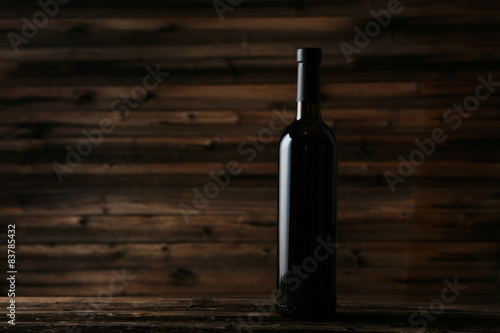 Bottle of red wine on brown wooden background