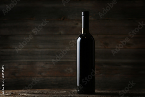 Bottle of red wine on grey wooden background